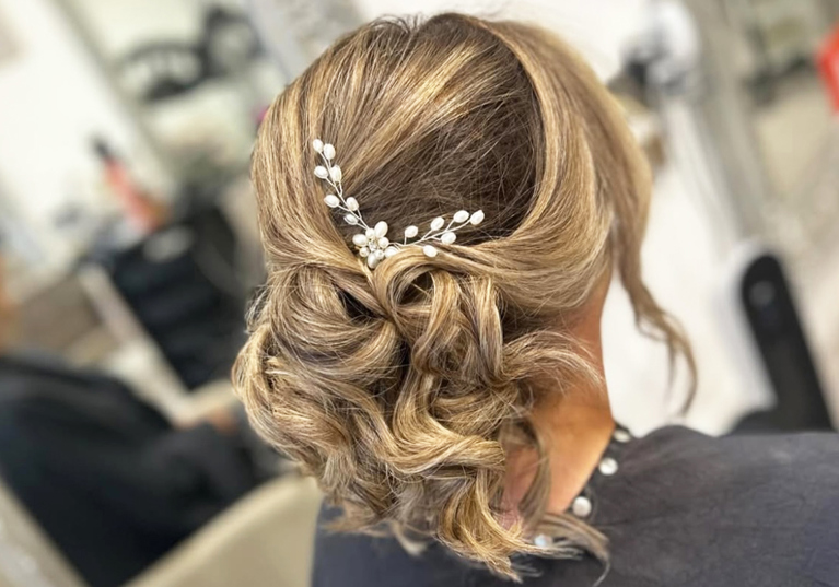 Updo with white flower-inspired hair accessory on girl